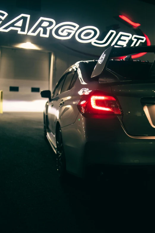 the back end of a parked car under a neon sign