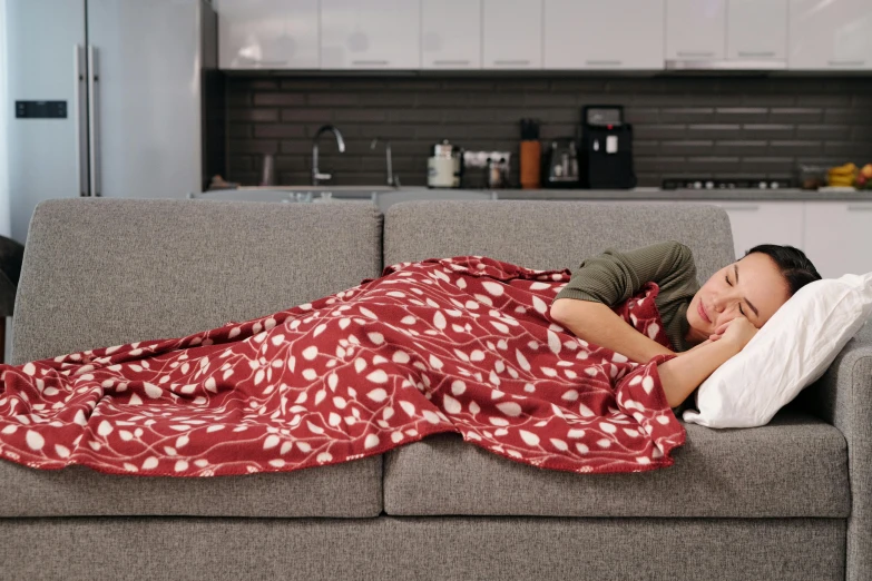 a woman is sleeping on a sofa next to the kitchen