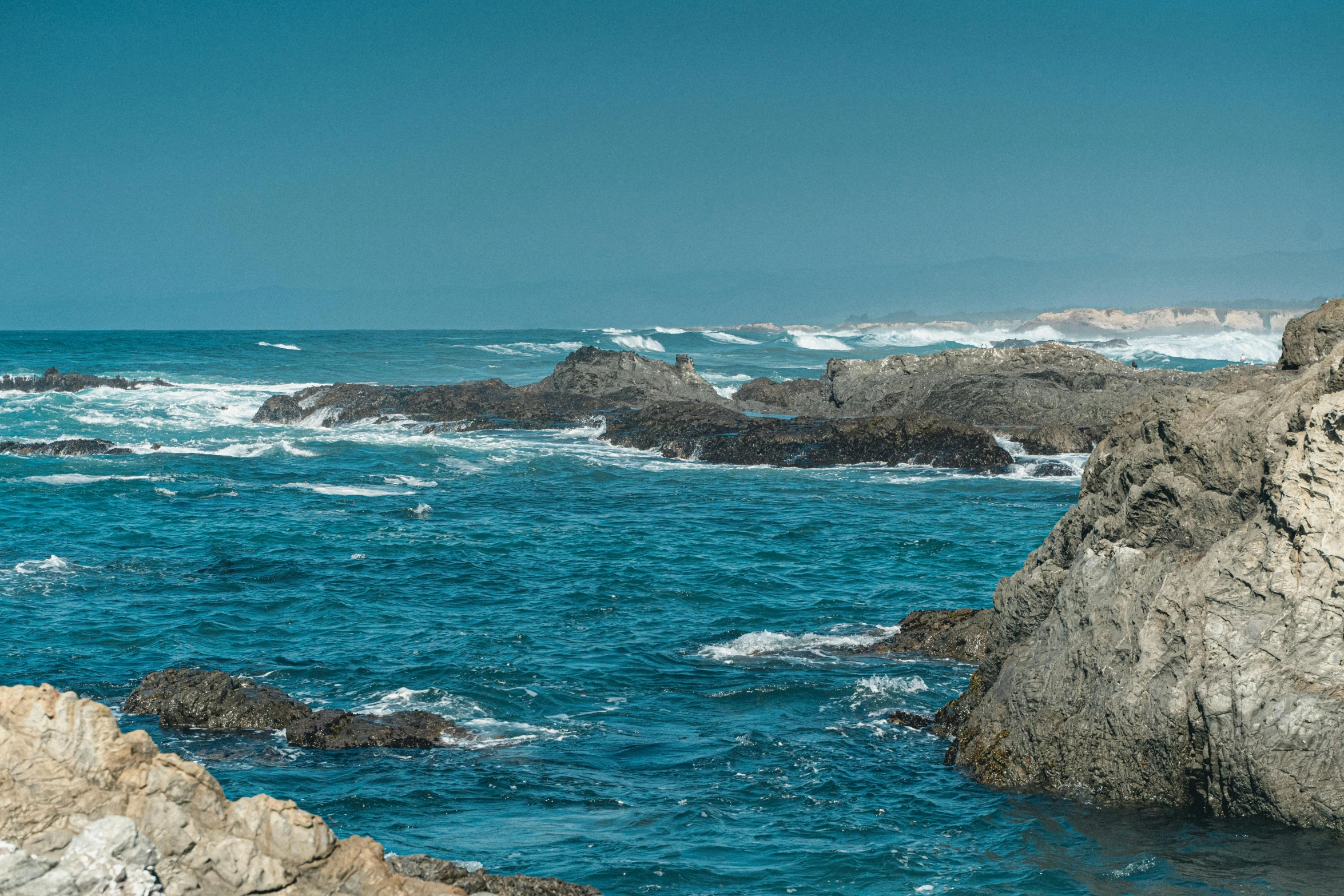 a group of rocks with a body of water next to it