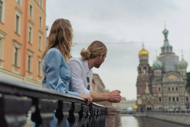 two girls looking down at soing while sitting on a bridge