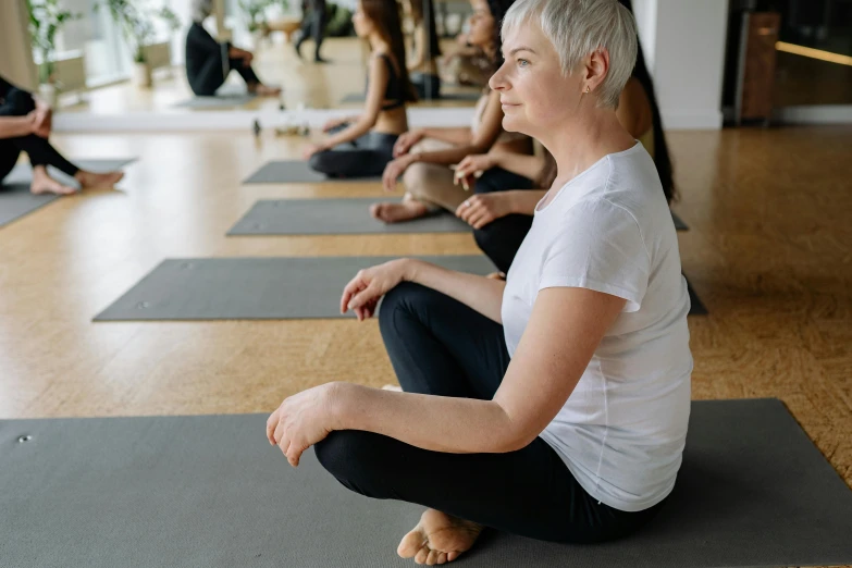 group of women in sitting yoga position in a large indoor setting