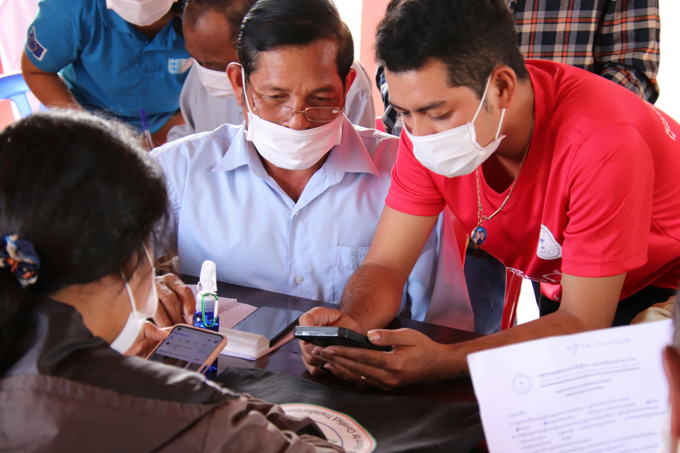 two people wearing face masks looking at a cell phone