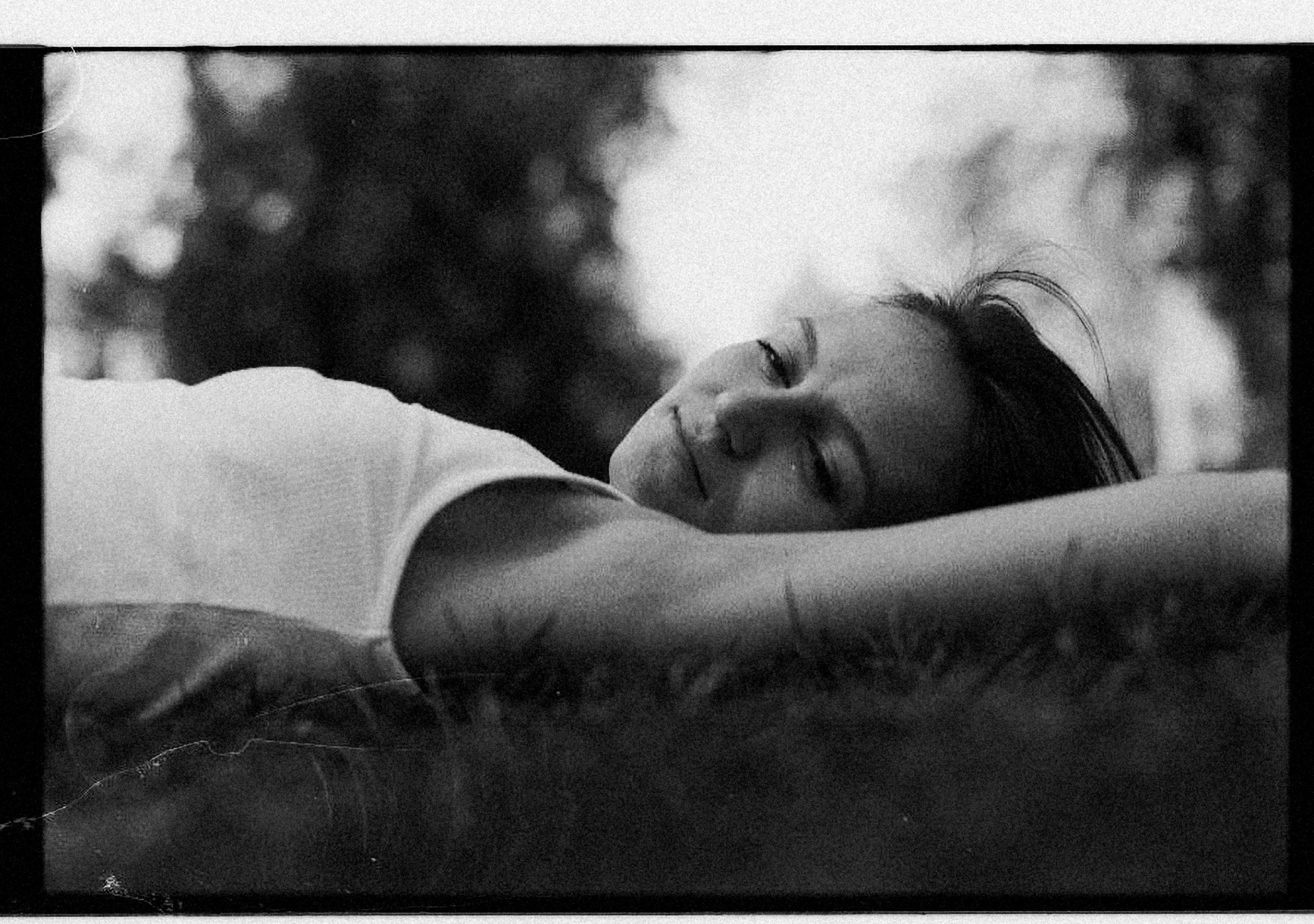 a black and white po of a person asleep on the grass