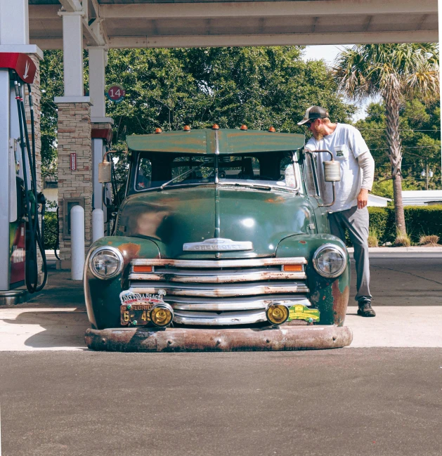 a man standing next to an old fashioned green truck