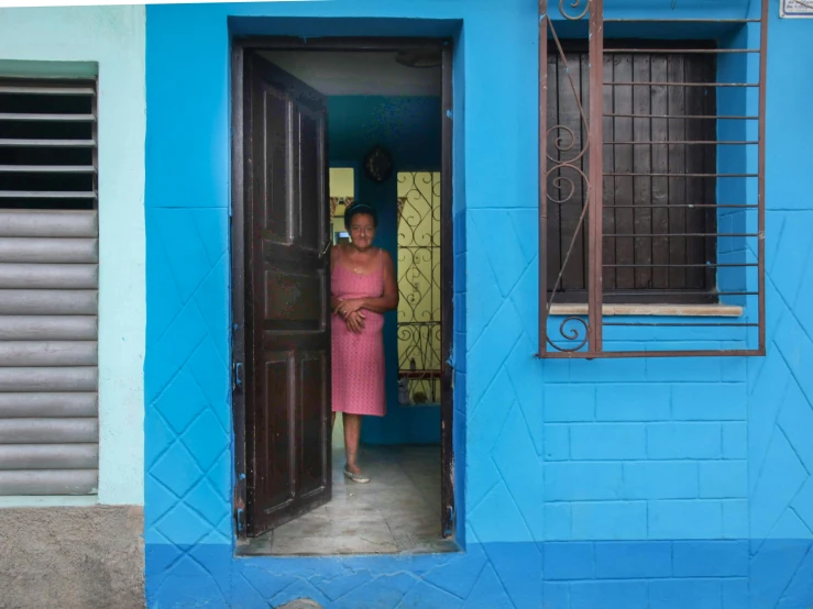 a woman stands at the door of a blue building