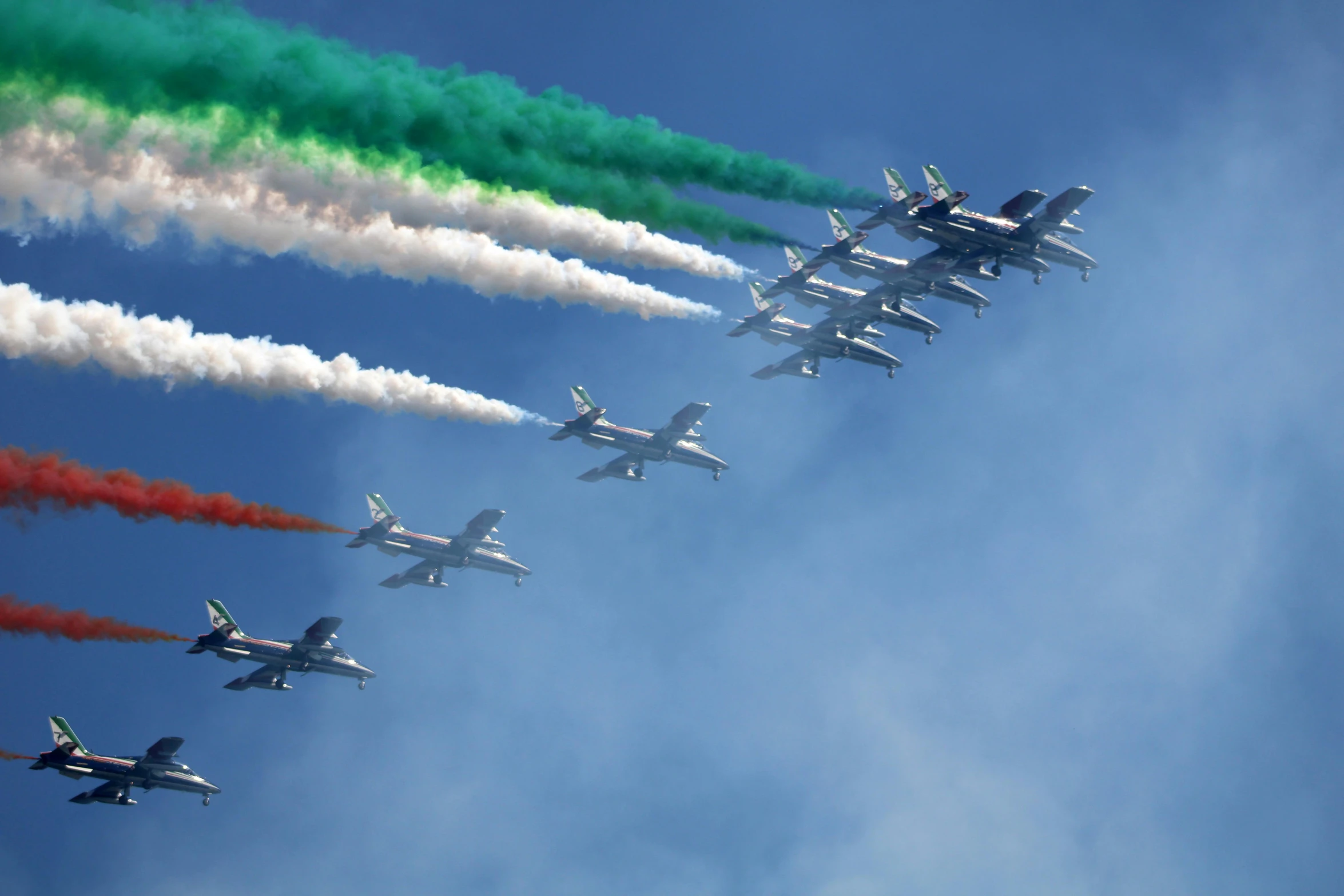 a group of planes flying in the sky with colored smoke