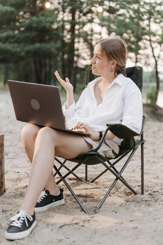 a woman using her laptop outside while sitting in a chair