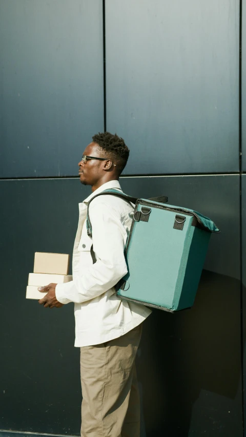 man carrying a box and a suit case on his back