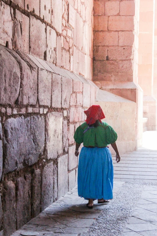 a woman in blue is walking up the side walk