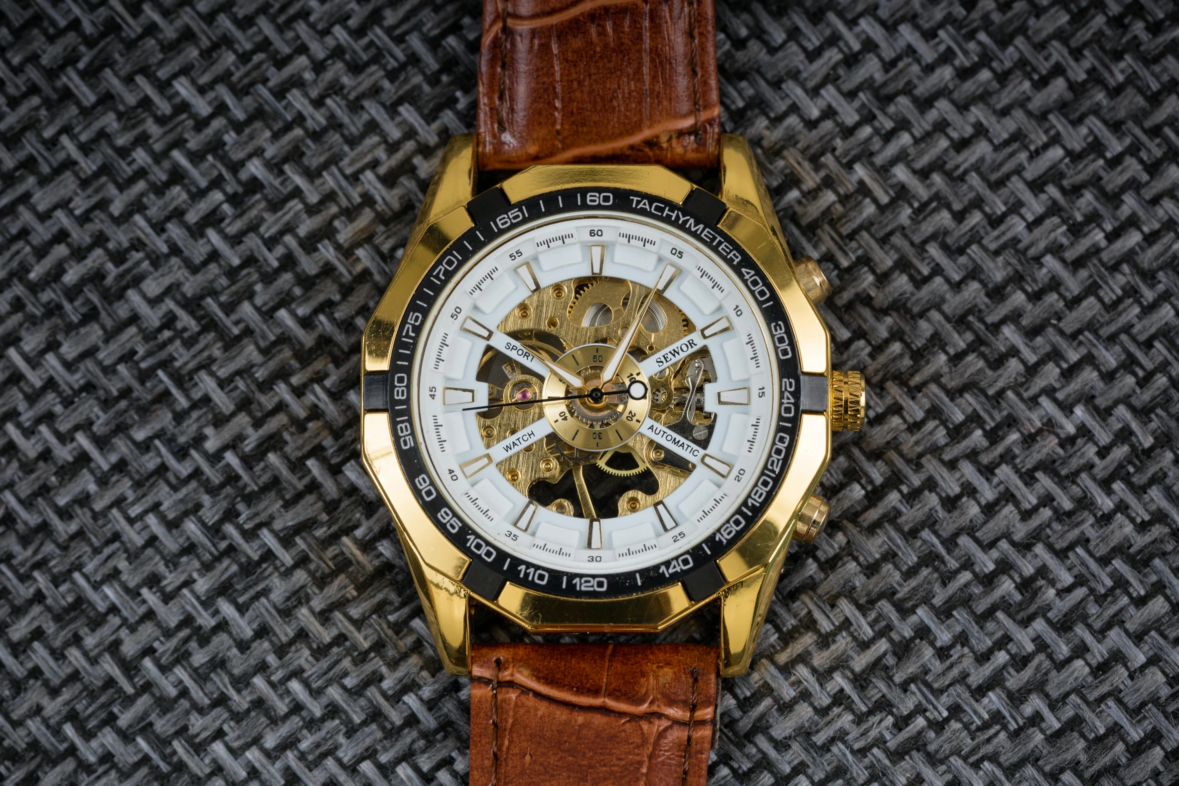 a watch with a yellow bezel sitting on top of brown leather
