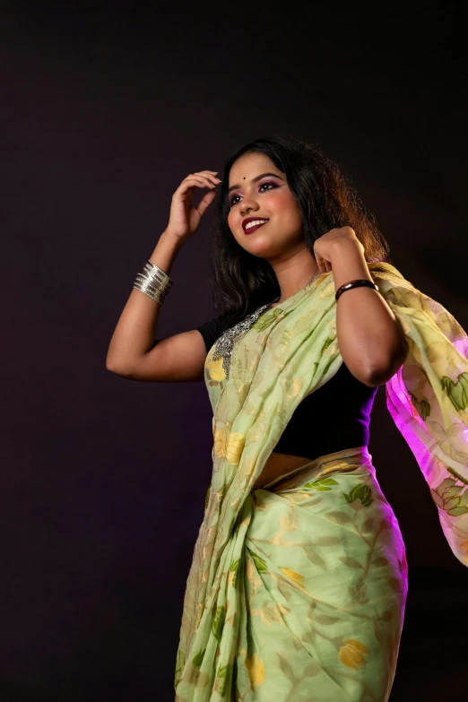 a woman standing with her arms around her waist in an abstract green sari