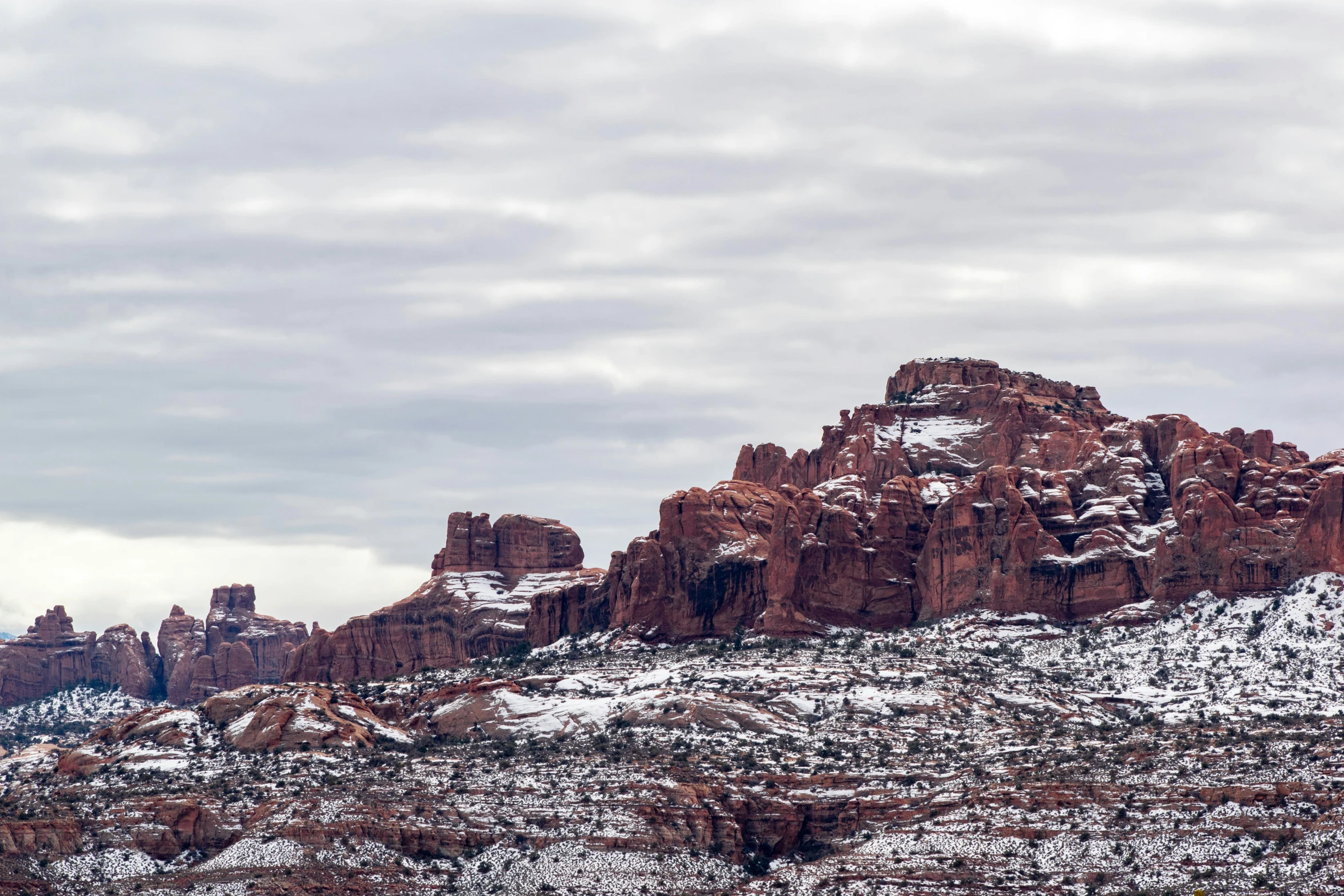 a rocky mountain covered in snow under a cloudy sky