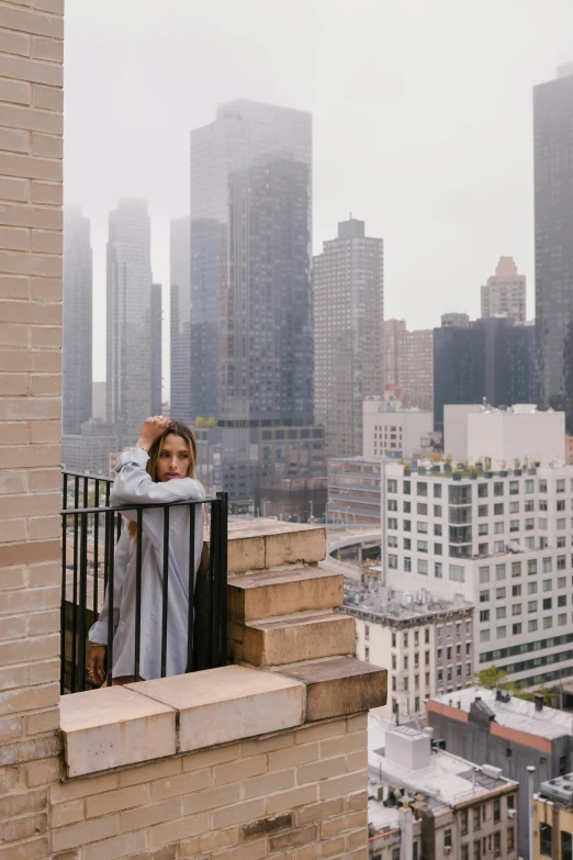 a young woman covers herself from the sun with a towel as she is overlooking the city skyline