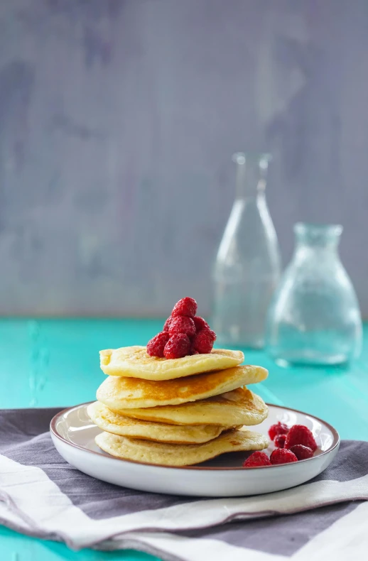 stack of pancakes with raspberries on top of a plate