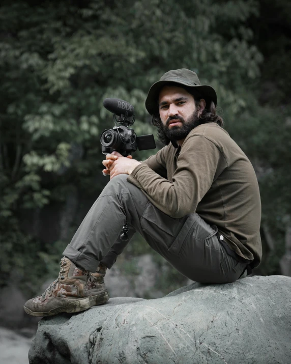 a man sitting on a rock while holding a camera