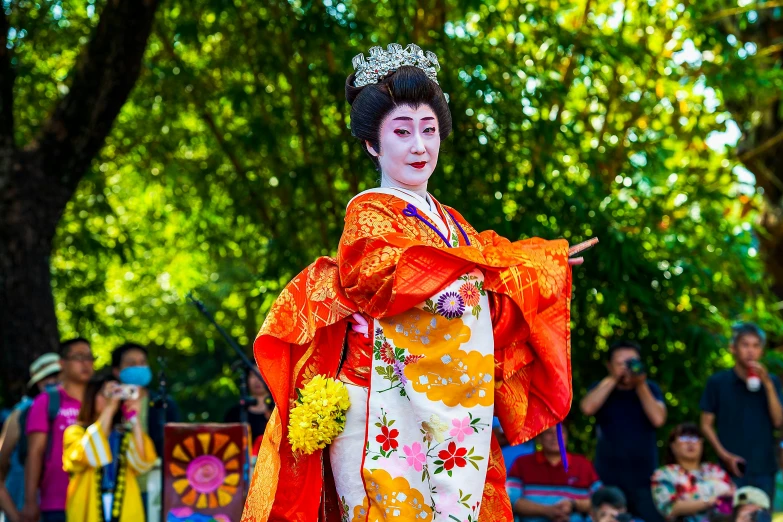 the queen in orange attire is performing for the crowd