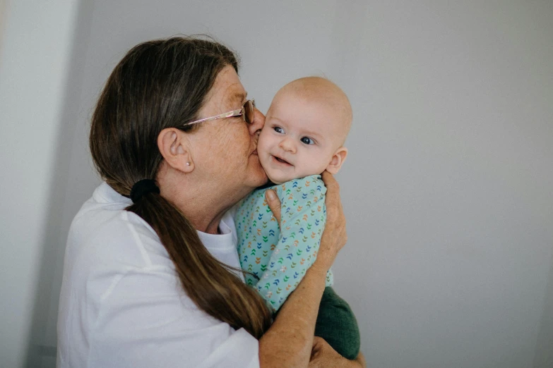 a woman is holding her baby while she kisses the cheek