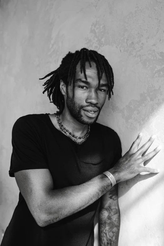 a young man with dreadlocks stands by the wall