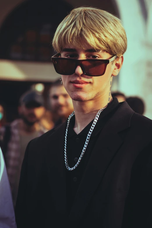 man in sunglasses looking at camera on crowded sidewalk