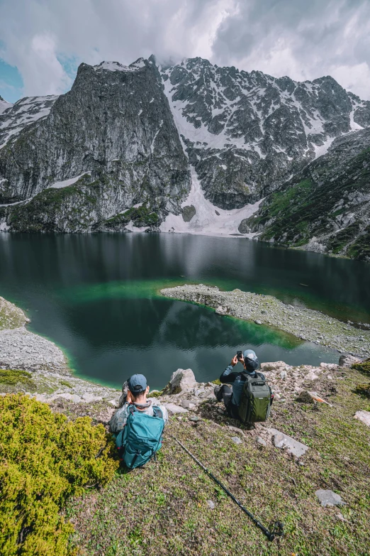 two mountain climbers overlooking a green lake in the high country