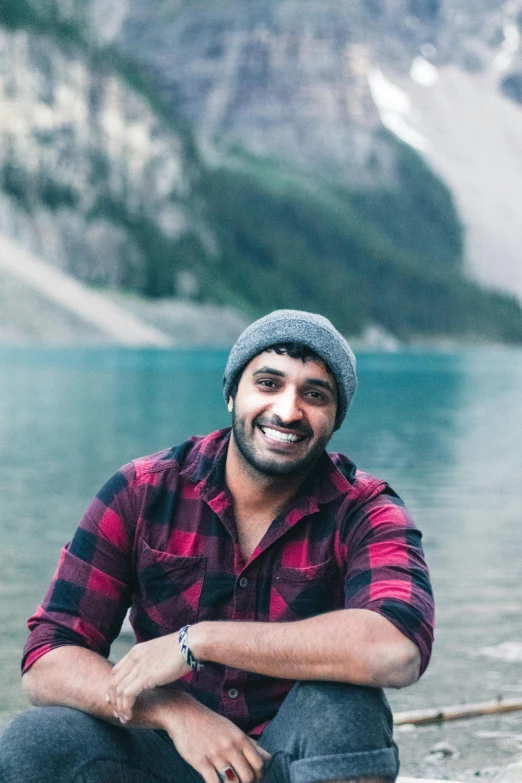 man sitting on beach wearing a plaid shirt