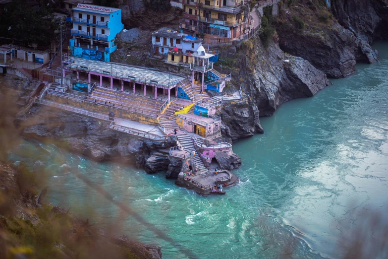 a view of a cliff, a river and several buildings next to each other