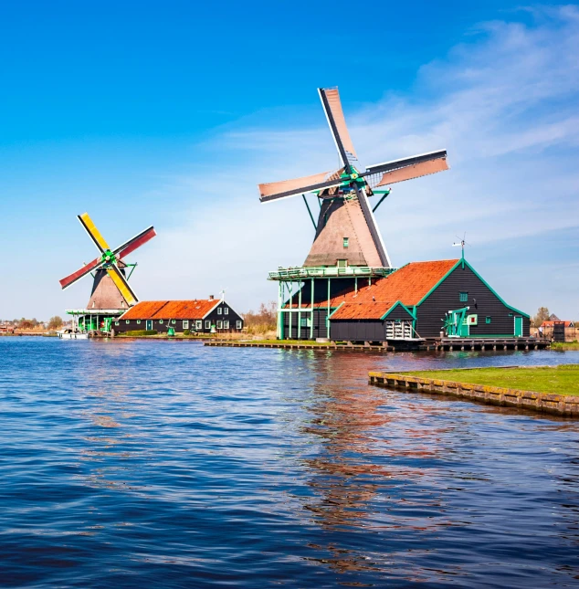 three windmills on the shore of a body of water