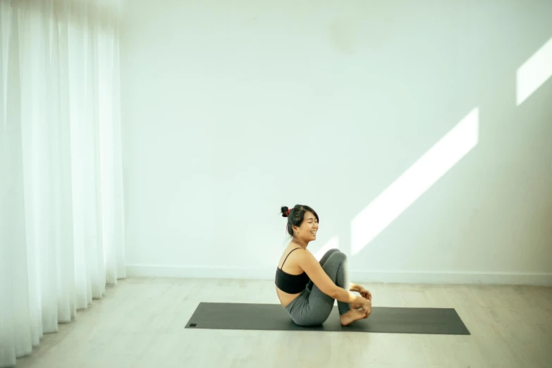 a girl practices yoga on her mat in an empty room