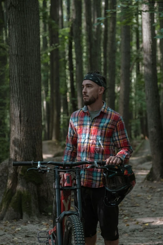 man walking in the woods with his bicycle