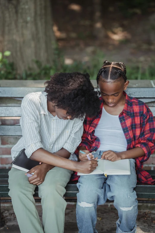 two women sitting on a bench with papers and pen