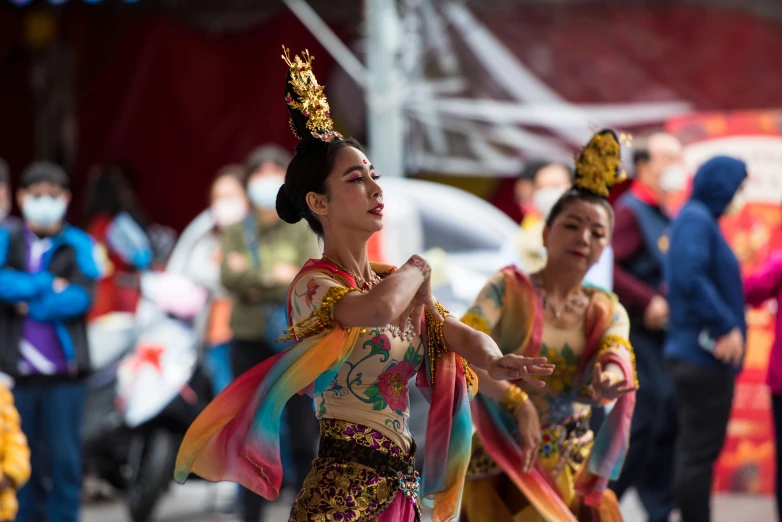 two beautiful women with head pieces dancing and others looking on