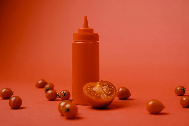 tomatoes scattered around an orange bottle with the top half half opened