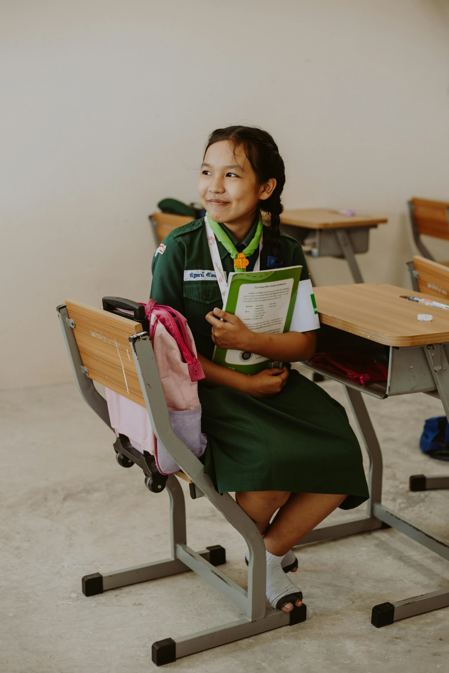 a little girl in green sitting at a desk with some books