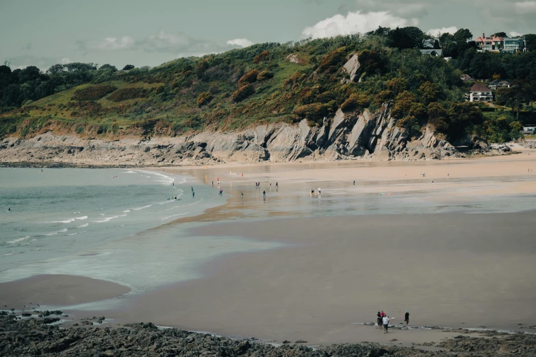 several people standing on the beach watching others swim