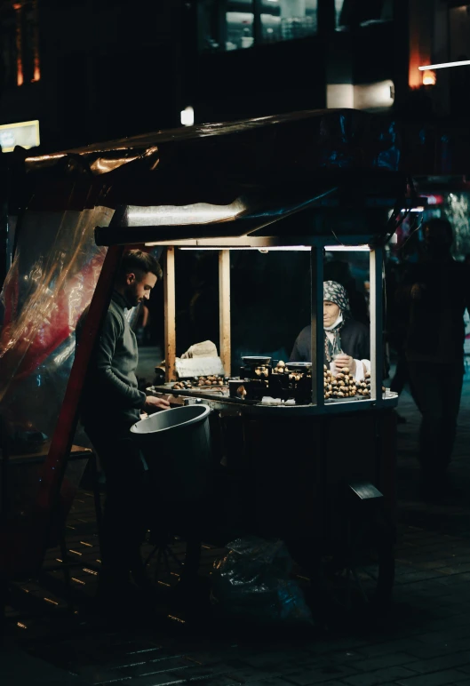 there is a man standing outside of a small food stand