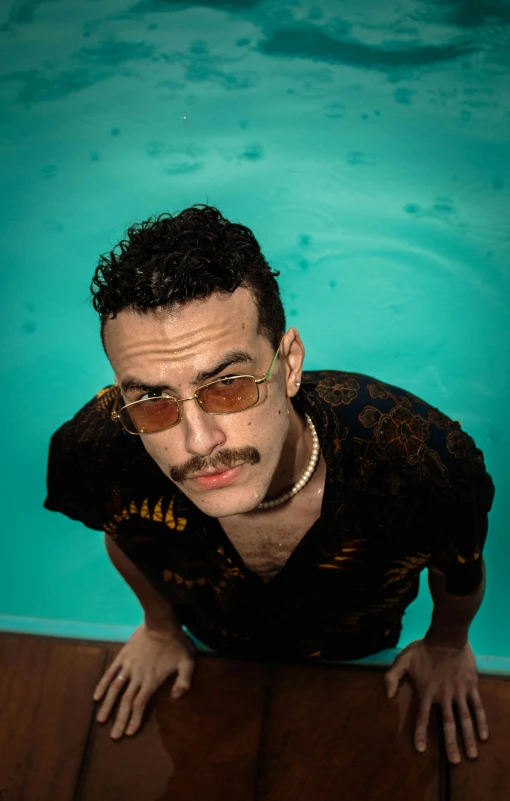 a man with sunglasses and a beard leaning over a pool