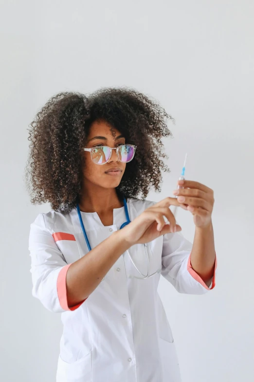 a woman standing wearing glasses and holding soing in her hand