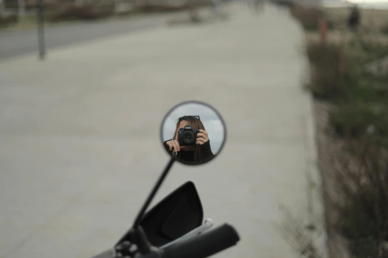 a motorcycle mirror showing the reflection of a person