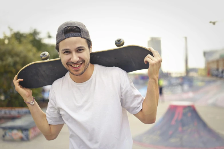 a man is smiling and holding his skateboard