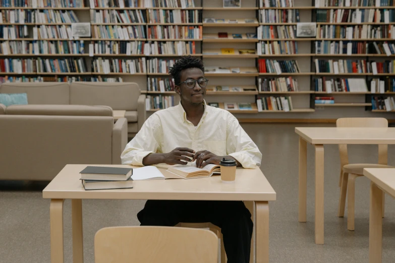 a black woman sits at a desk in a liry