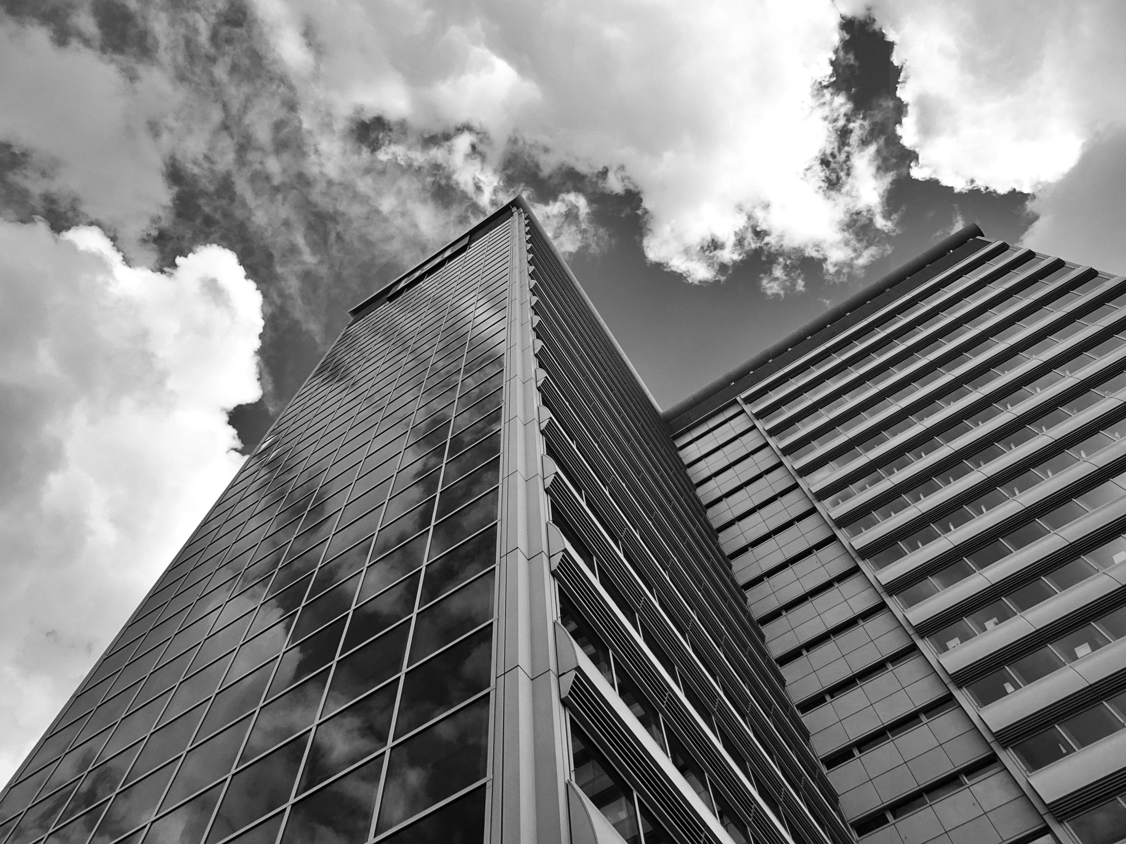 black and white pograph of office building against cloudy sky