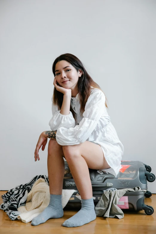 a woman sitting on the suitcase in her room