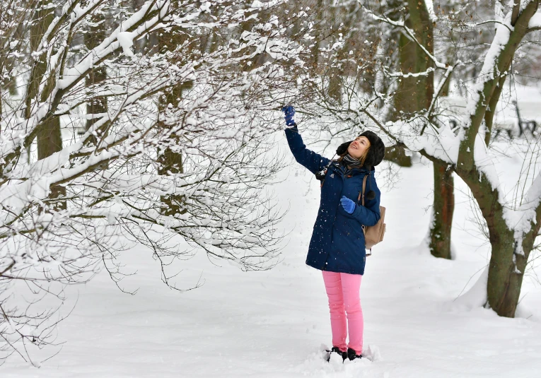 a person standing in a snowy field with her arms raised