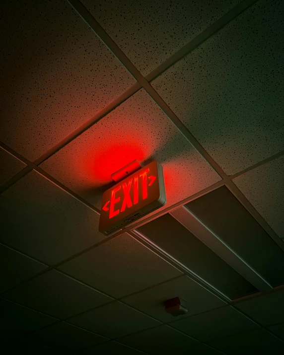 an exit sign on a ceiling with a red light and a stop light