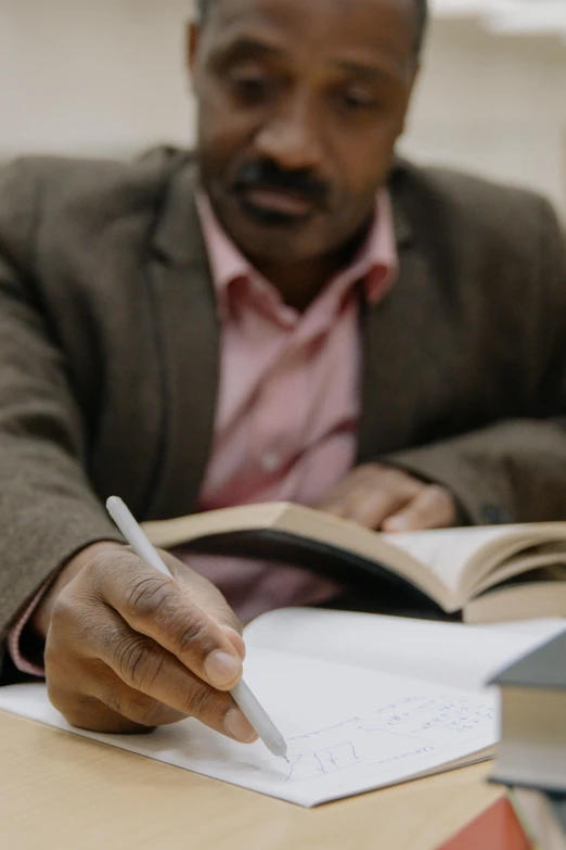 man sitting at a table writing on a book