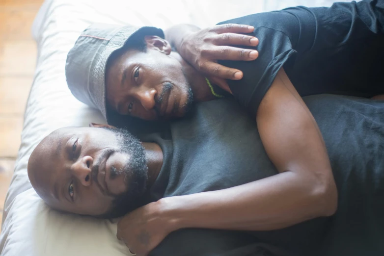 a couple of men laying on top of a bed