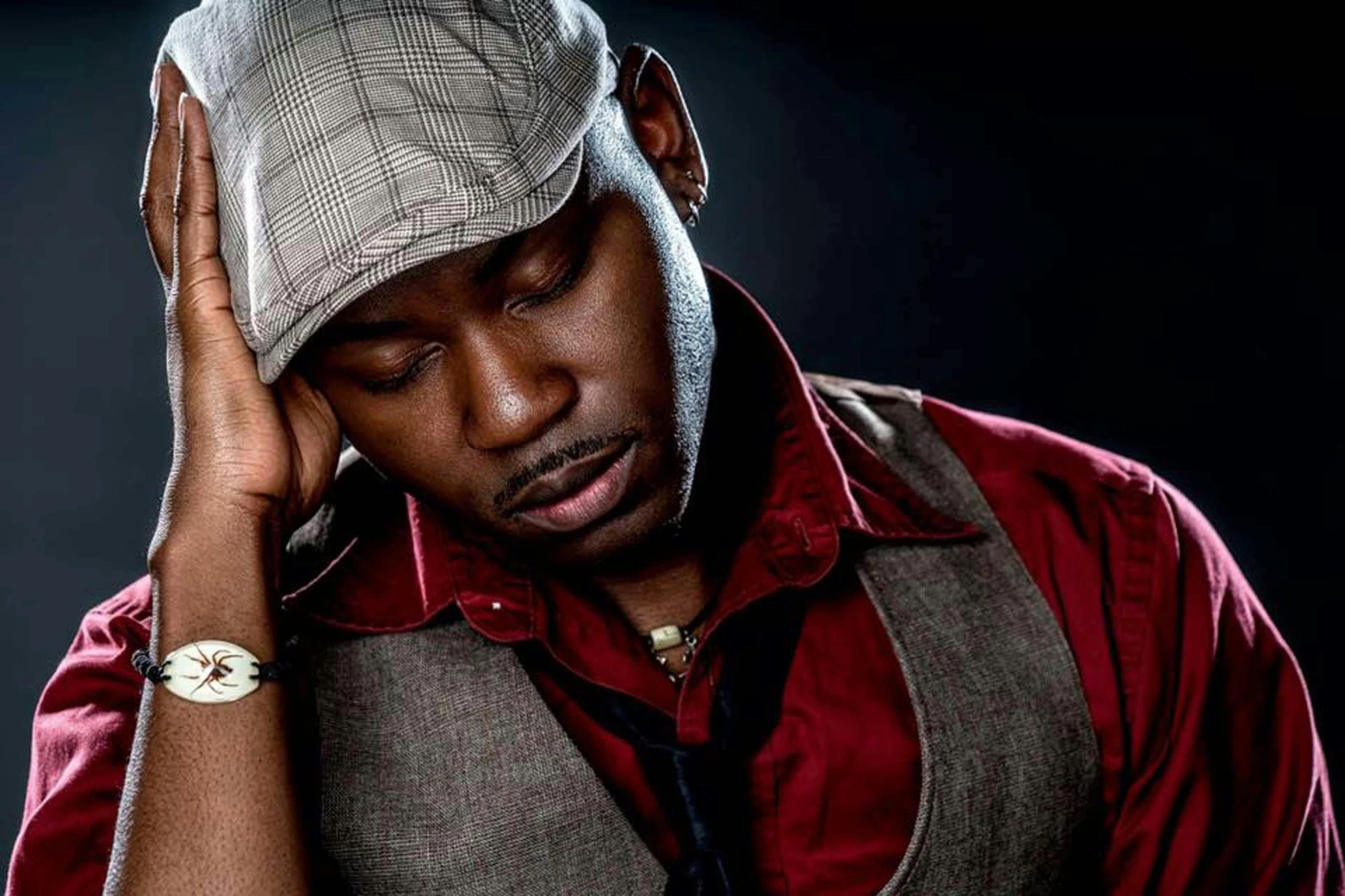 a man with a tie and vest is holding his hat