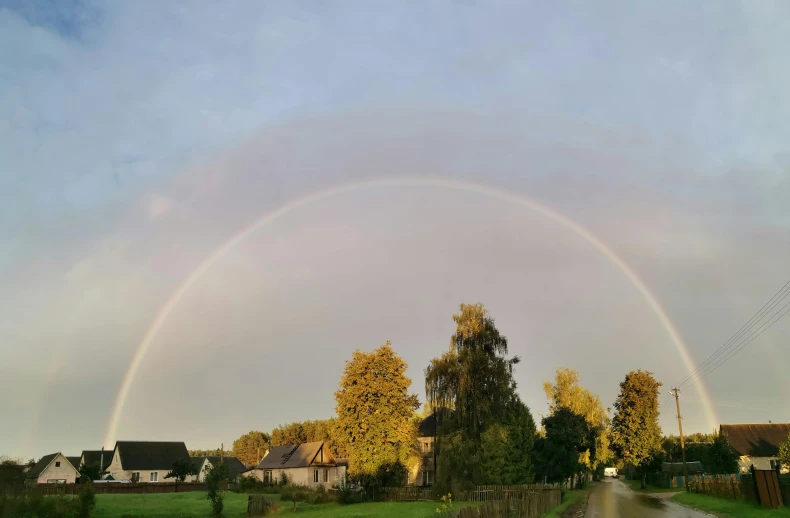 a large rainbow shines over a neighborhood