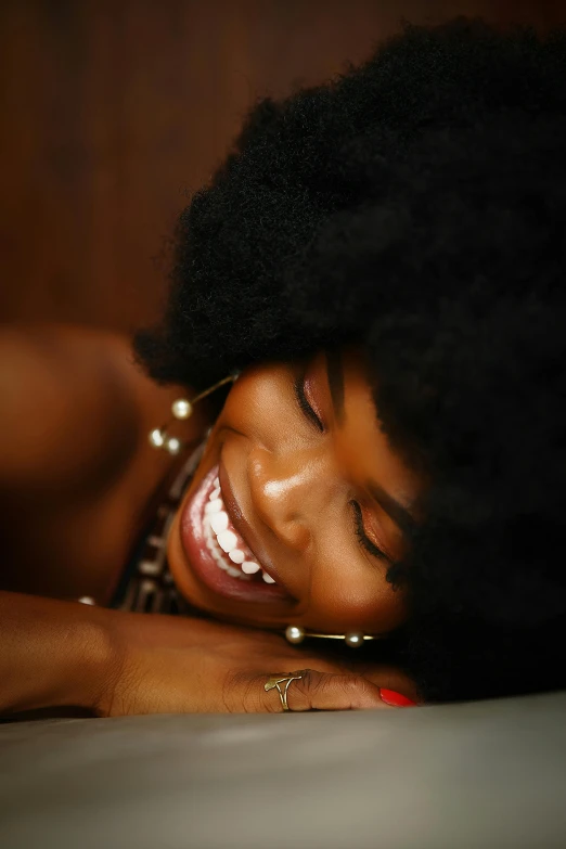 a close - up view of an afro woman with her hand on her cheek and one eye closed