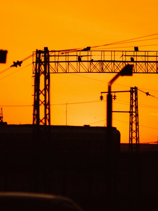 the silhouette of cranes at sunset behind wires